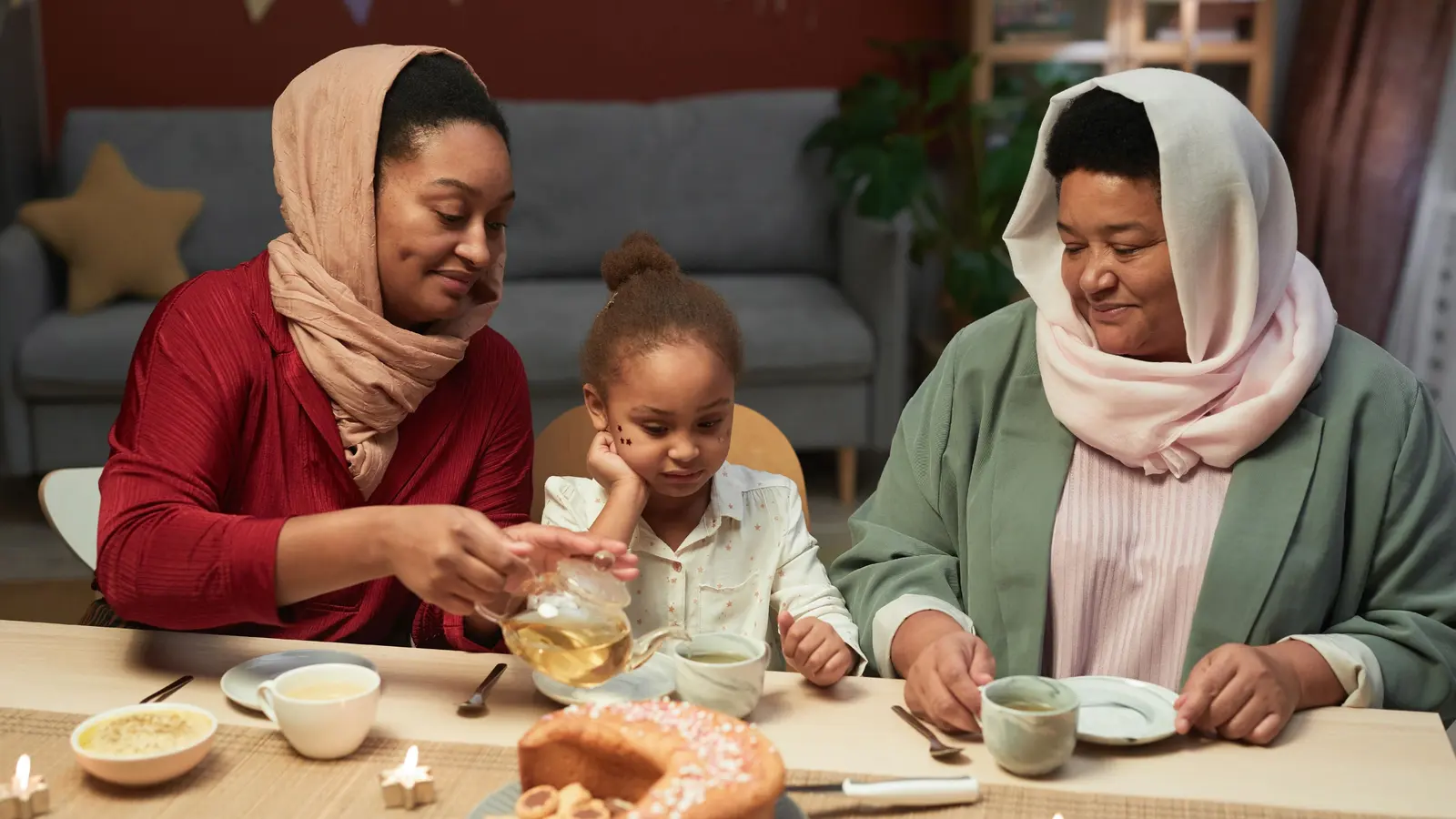 An older woman and her adult daughter share tea at the family table, a young granddaughter sitting between them.
